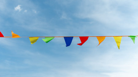 Festive ribbon made of multicolored triangles on the background of the sky.