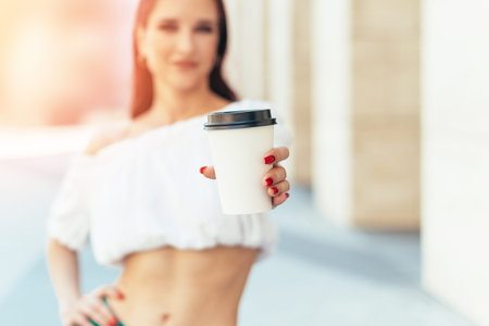 Caucasian girl holds out a glass of coffee in summer.の写真素材