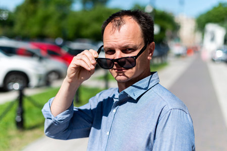 Caucasian man forty years old businessman on the street takes off his sunglasses.