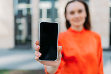 Caucasian girl smiling shows smartphone screen with copy space