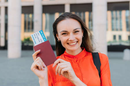 Caucasian girl joyful holding passport with air ticket for the plane in her hands.の写真素材