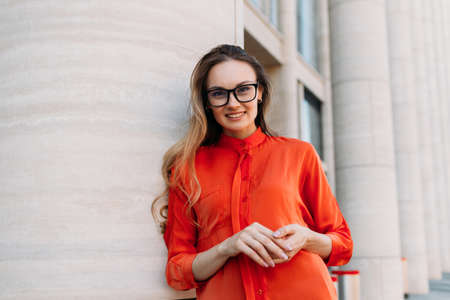 Young woman wearing glasses next to modern building.の写真素材