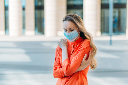 Caucasian girl with closed eyes in medical mask with headache.