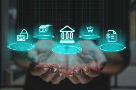 Online banking concept with futuristic design and graphics over hands. Financial icons as a projection of the imageの写真素材