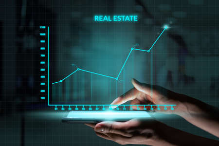 Business investment concept. Person holding smartphone with Abstract graph real estate growth.の写真素材