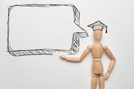 webinar concept. Wooden puppet with a hat of knowledge and bubble