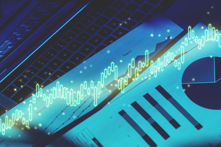 The concept of stock trading and dynamics on charts on the background of documents with a laptop.