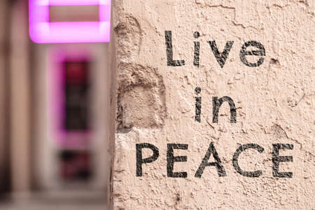 Inscription live in peace. The inscription on the wall of the buildingの写真素材