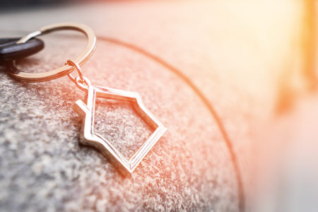 A keychain in the shape of a house lies on the granite facade of the building.