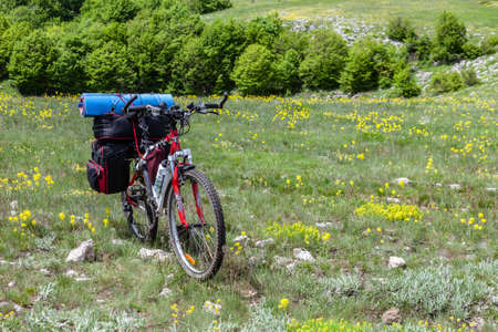 Plateau Karabi, Ukraine, May 2011: A lone mountain bike with a backpack stands on a hilly terrain. A concept of cycling travel, World Bicycle Day (June, 3). Equipment for cycling tourism.のeditorial素材