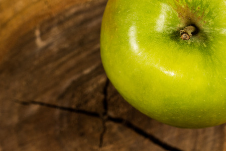 Green apple on a piece of wood cutの写真素材