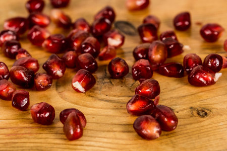 Pomegranate seeds on a rustic wooden table