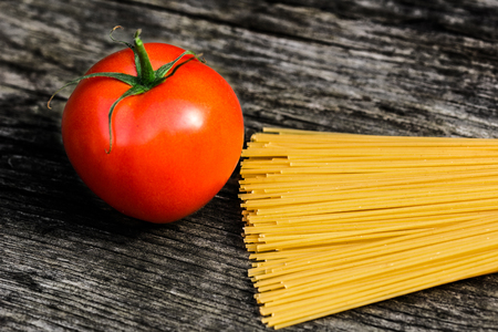 Spaghetti and tomato on a rustic wooden benchの写真素材