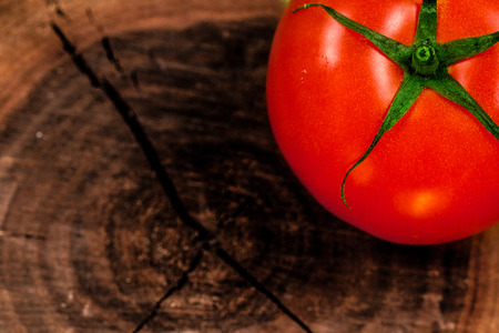 Fresh tomato on a tree trunk cutの写真素材