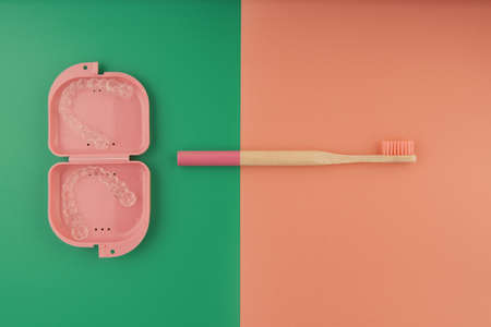 Wooden toothbrushes on colored background and transparent aligners, invisible orthodonticsの写真素材