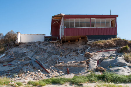 summer home falling into the beach in northern Jutlandの写真素材