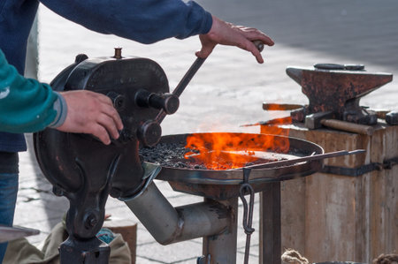 metalsmith blowing air on the fire