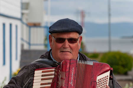 Hrisey Iceland - July 8. 2016: Old man playing red Harmonica during local festivalのeditorial素材