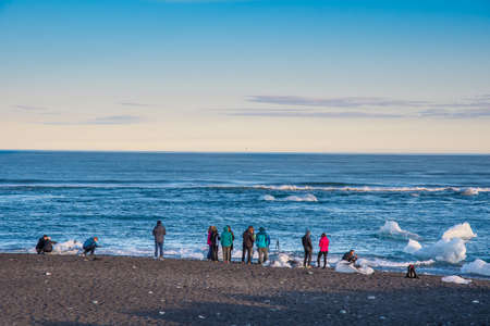 Jokulsarlon Iceland - August 18. 2018: Tourist looking at ice at Diamond beach in Icelandのeditorial素材