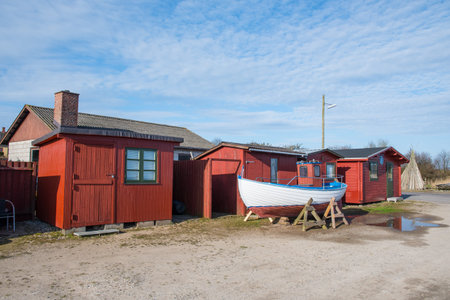 old fishing boat in front of red sheds in port of Kalvehave in Denmark