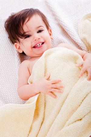 Baby lying down after bath in a yellow towelの写真素材