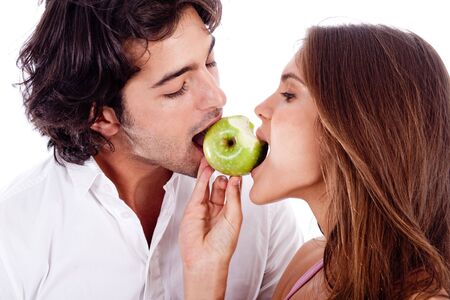 closeup of young couple playfully biting green appleの写真素材