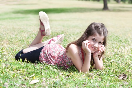 happy cute girl  laying on a grass field and looking stright ,outdoorの写真素材