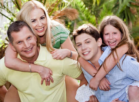 Loving father and son gives piggyback to their wife and daughter at the backyardの写真素材