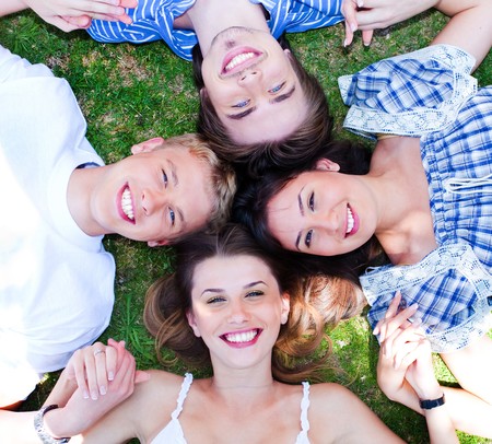 Young friends forming a circle making park as their bed and holding each others handsの写真素材