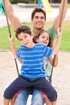 Father and children enjoying swing ride on a sunny dayの写真素材