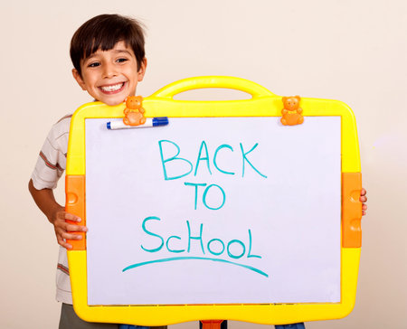 Yoing boy holding a whitebaord with text back to school on it