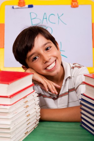Young happy student with stack of books on the tableの写真素材