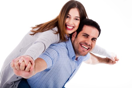 Portrait of young man giving piggyride to her girlfriend against isolated white backgroundの写真素材