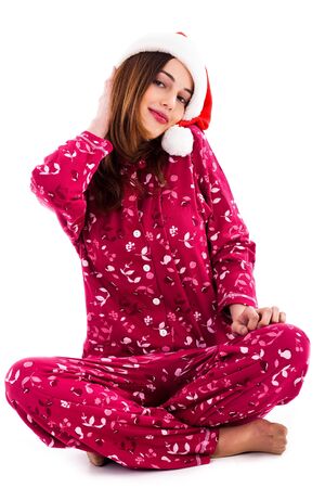 front view of young lady posing with santa hat sitting on floor on an isolated backgroundの写真素材