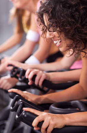Four people on bicycles in a gym or fitness club for a workout.の写真素材