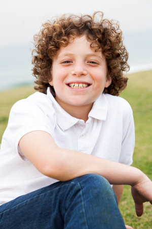 Young beautiful boy sitting in lawn
