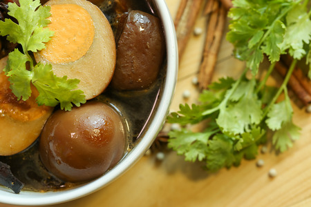 Stewed eggs  and pork brown sauce in white bowl by Thai food and blur spices on wood background.の写真素材
