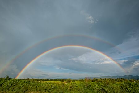 beautiful double rainbow on clouds  rainy day in rice field. after rain concept fresh airの写真素材