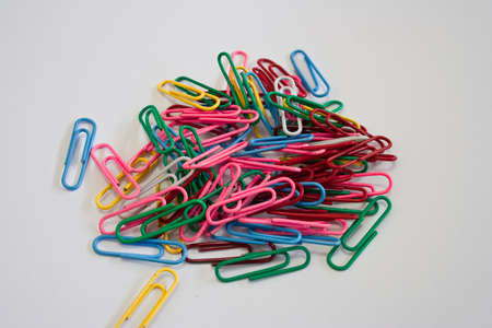 Colourful paper clips on a white background with space for text