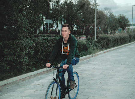 A man riding a bicycle in a park in cloudy weatherの写真素材
