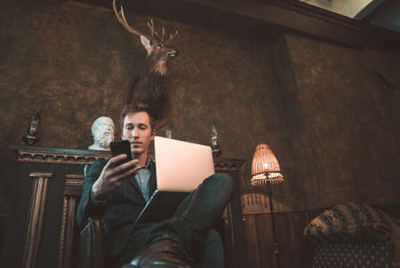 A man is working at a computer and talking on the phone in the background of a fireplaceの写真素材