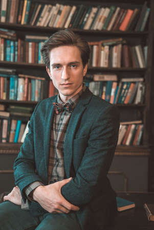 Portrait of a man in a jacket on the background of booksの写真素材
