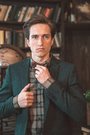 Portrait of a man in a jacket on the background of booksの写真素材