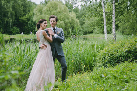 The bride and groom stand near a lake in the parkの写真素材