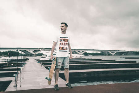 A man is riding a skateboard on a pier in a yacht club near the riverの写真素材