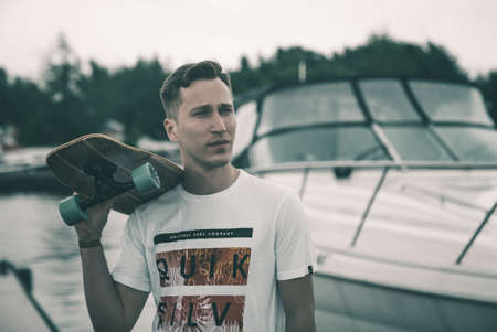 A man is riding a skateboard on a pier in a yacht club near the riverの写真素材