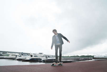 A man is riding a skateboard on a pier in a yacht club near the riverの写真素材