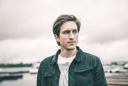 Portrait of a man in a jeans standing on a pier near the yachtの写真素材