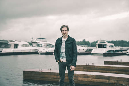 Portrait of a man in a jeans standing on a pier near the yachtの写真素材
