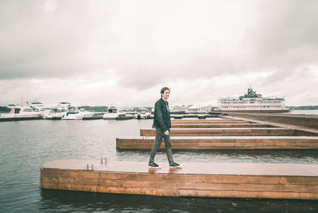 Portrait of a man in a jeans standing on a pier near the yachtの写真素材